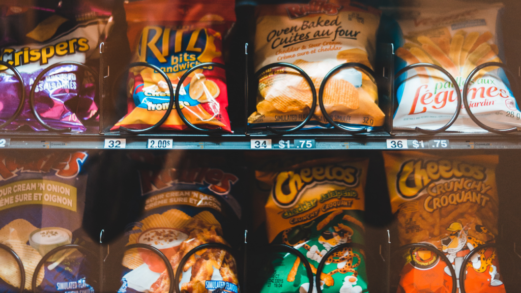 Vending machine stocked with assorted chips and snacks including Cheetos, Ruffles, and Ritz Bits.