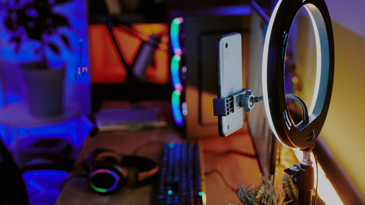 Ring light with smartphone mount set up on a desk for streaming and content creation with colorful RGB background lighting.