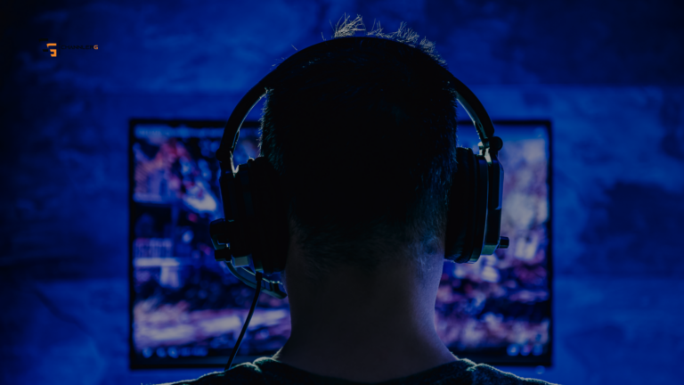 Gamer wearing a headset in front of a dual-monitor setup glowing blue.