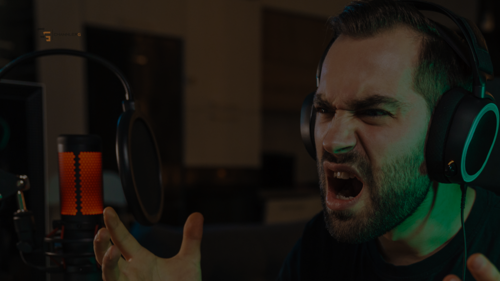 Frustrated gamer yelling into a headset while streaming with a red-lit microphone in front of him.