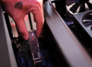 Hand installing Samsung 990 PRO NVMe SSD into a gaming PC.