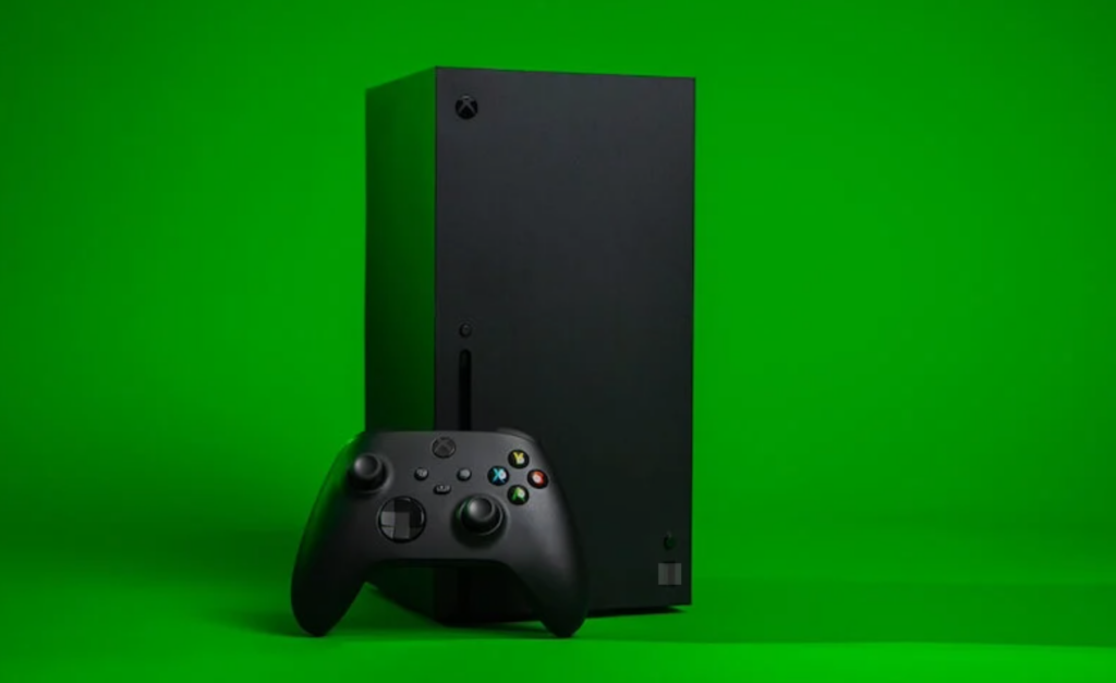 Xbox Series X console standing vertically with a wireless controller against a bright green background.
