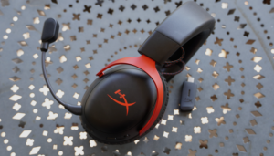 HyperX gaming headset with detachable microphone and USB wireless adapter on metal table.