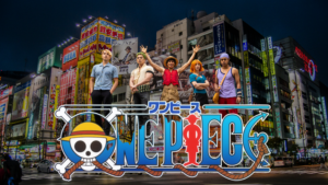 Live-action One Piece cast standing in a city at night with bright neon signs, featuring Luffy and crew above the One Piece logo.