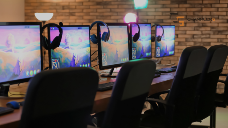 Row of gaming PCs with monitors and headsets set up in a multiplayer gaming room, resembling a LAN party or esports gaming setup.