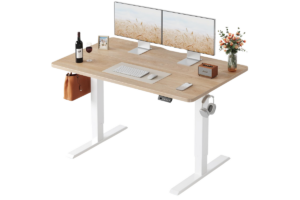 FEZIBO electric standing desk with light wood desktop, dual-monitor setup, adjustable height frame, headphone hook, and modern ergonomic home office workspace.