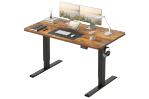 CubiCubi electric standing desk with rustic wood desktop, dual monitor setup, adjustable height frame, desk lamp, tablet stand, and modern home office workspace accessories.