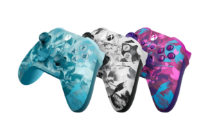 Three colorful Xbox wireless controllers in blue, black and white, and pink designs